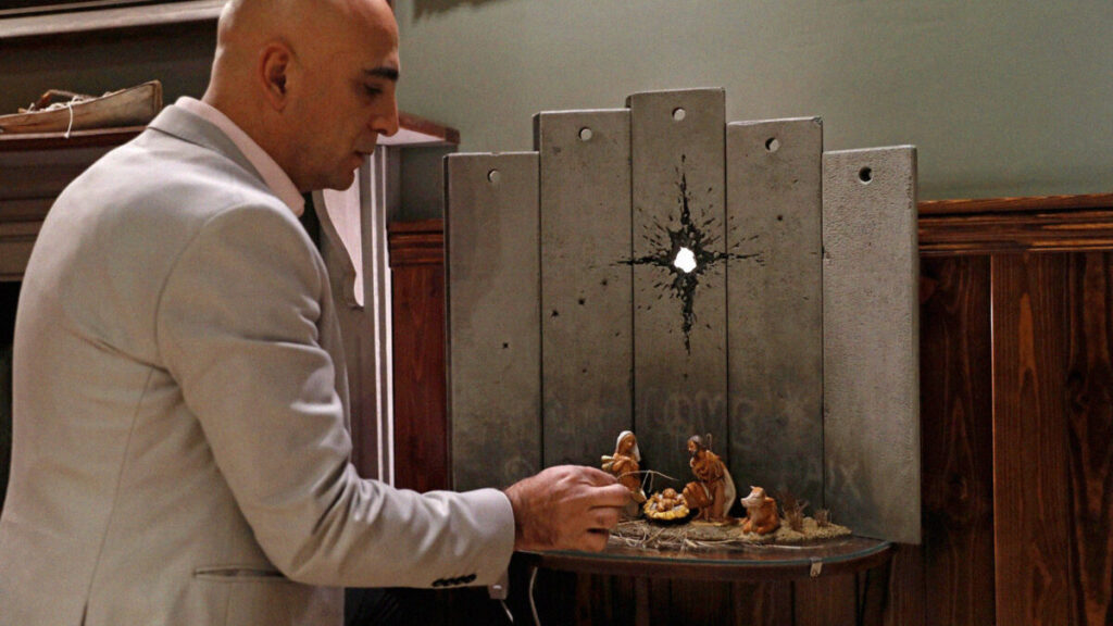 Wissam Salsaa, gerente del hotel Walled Off, muestra la obra de Banksy. Fotografía: Mussa Qawasma.