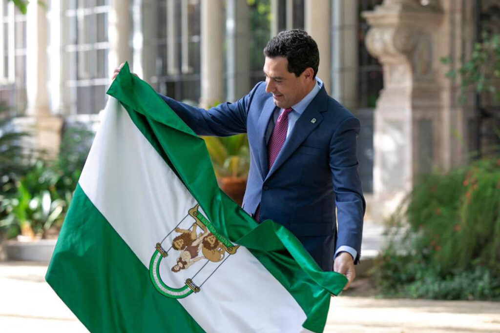El presidente de la Junta, Juanma Moreno, con la bandera de Andalucía. Fotografía: Julio Muñoz.